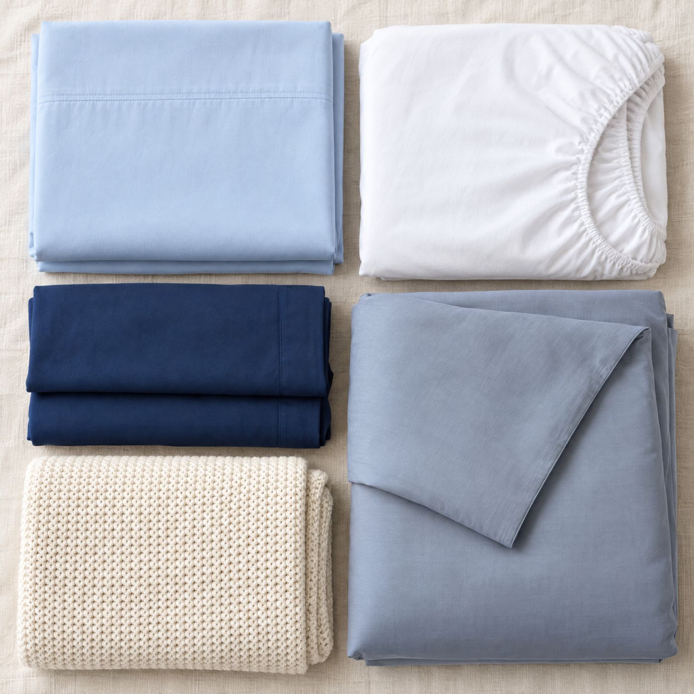 Neatly folded clean sheets, pillowcases, a duvet cover and a blanket